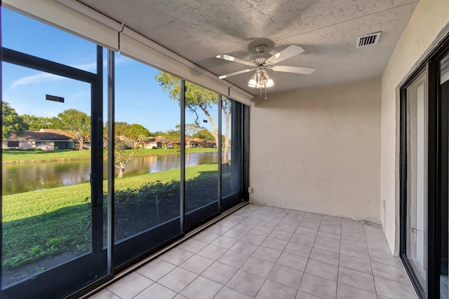 unfurnished sunroom with ceiling fan, a water view, and plenty of natural light