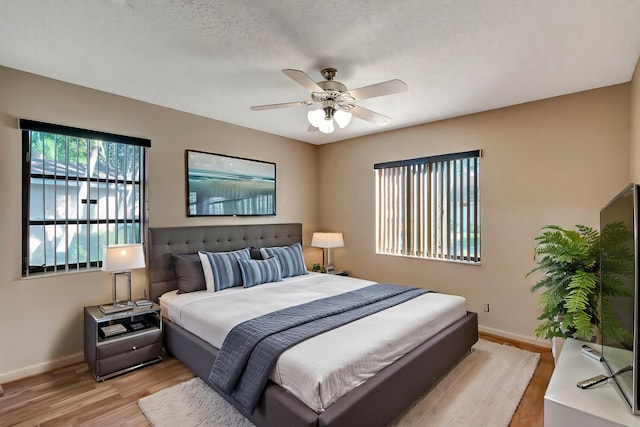 bedroom with ceiling fan, light hardwood / wood-style floors, and a textured ceiling