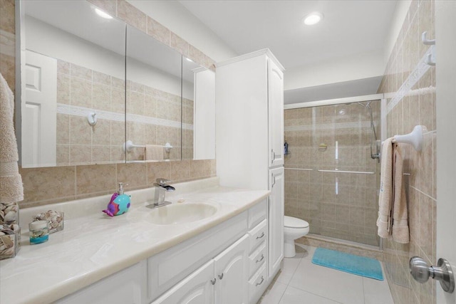 bathroom with an enclosed shower, vanity, tile walls, tile patterned flooring, and toilet