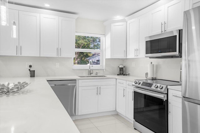 kitchen featuring sink, stainless steel appliances, light tile patterned floors, pendant lighting, and white cabinets