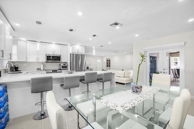 tiled dining area featuring a textured ceiling, sink, and french doors