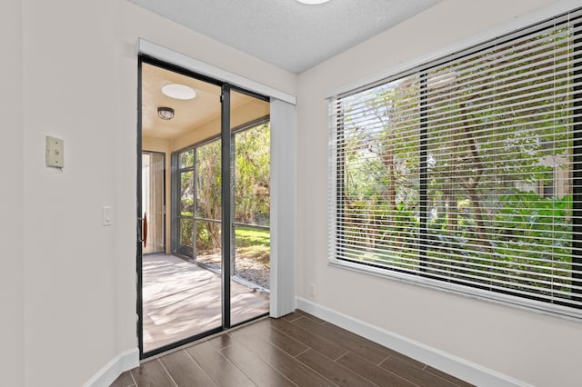 doorway to outside featuring dark hardwood / wood-style flooring and a textured ceiling