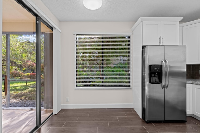 kitchen featuring white cabinets, decorative backsplash, stainless steel fridge, and a wealth of natural light