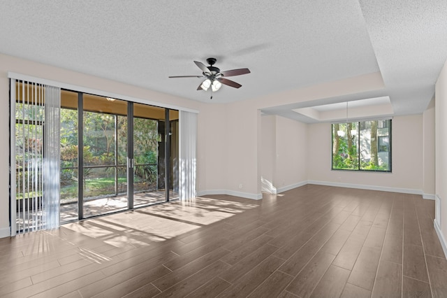 spare room with ceiling fan with notable chandelier, hardwood / wood-style flooring, and a raised ceiling