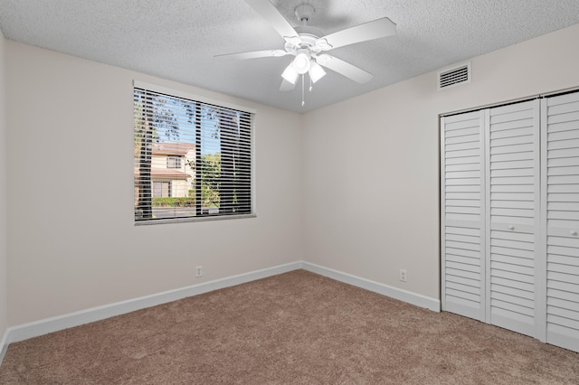 unfurnished bedroom with carpet flooring, ceiling fan, a closet, and a textured ceiling