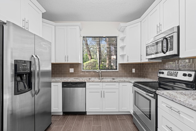 kitchen featuring white cabinets, sink, decorative backsplash, appliances with stainless steel finishes, and light stone counters