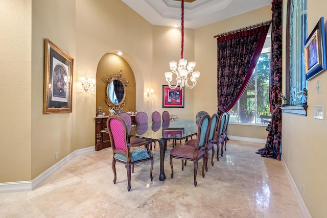 dining space featuring a towering ceiling, a tray ceiling, an inviting chandelier, and ornamental molding