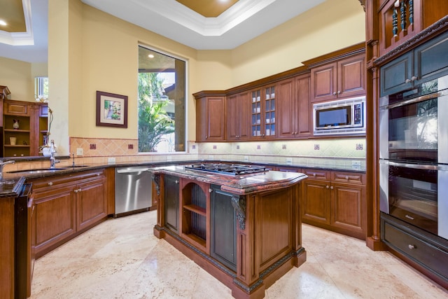 kitchen with dark stone counters, stainless steel appliances, and a tray ceiling