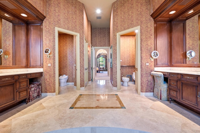 bathroom with vanity, toilet, a high ceiling, and a bidet