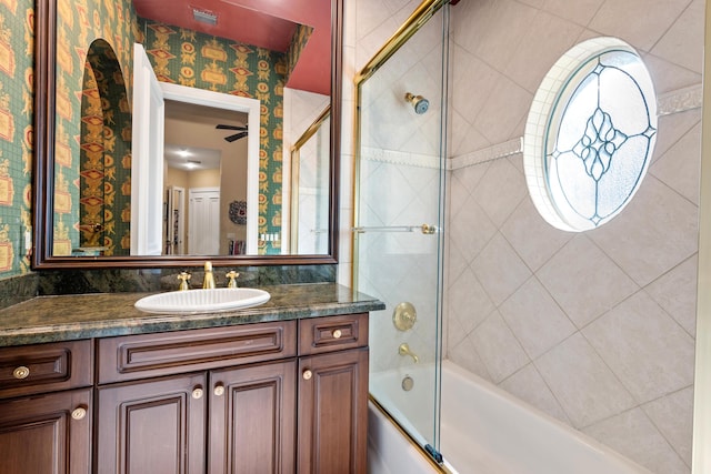 bathroom with ceiling fan, vanity, and bath / shower combo with glass door