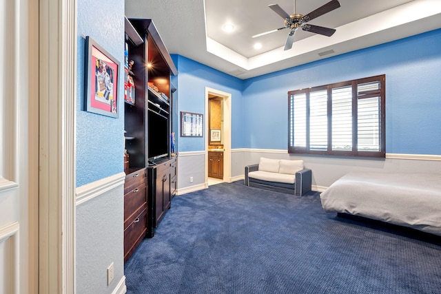 bedroom with carpet floors, ensuite bath, a raised ceiling, and ceiling fan