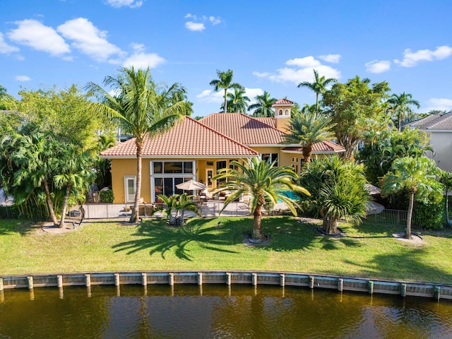 back of property with a lawn and a water view