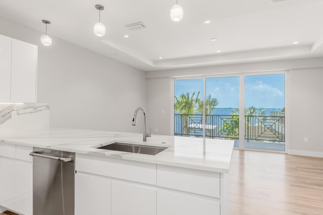 kitchen featuring light stone countertops, white cabinetry, sink, and hanging light fixtures