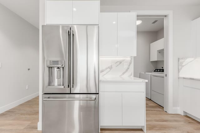 kitchen featuring washing machine and dryer, white cabinetry, light hardwood / wood-style flooring, and high end refrigerator