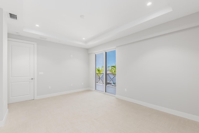 unfurnished room with a tray ceiling and light colored carpet