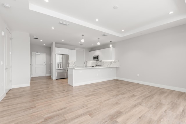 unfurnished living room featuring light hardwood / wood-style flooring, a raised ceiling, and sink