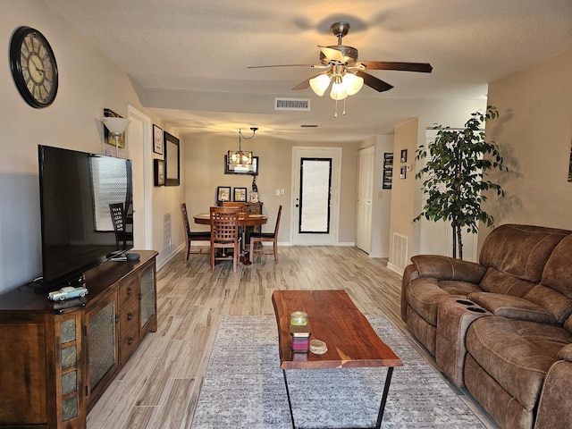 living room with a textured ceiling, ceiling fan with notable chandelier, and light hardwood / wood-style floors