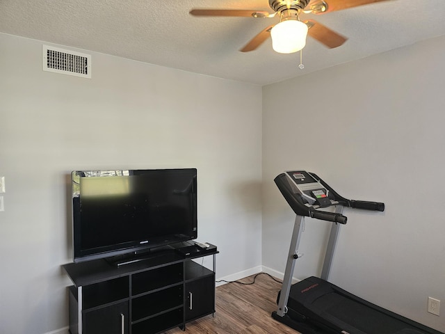 workout room with a textured ceiling, ceiling fan, and dark hardwood / wood-style floors