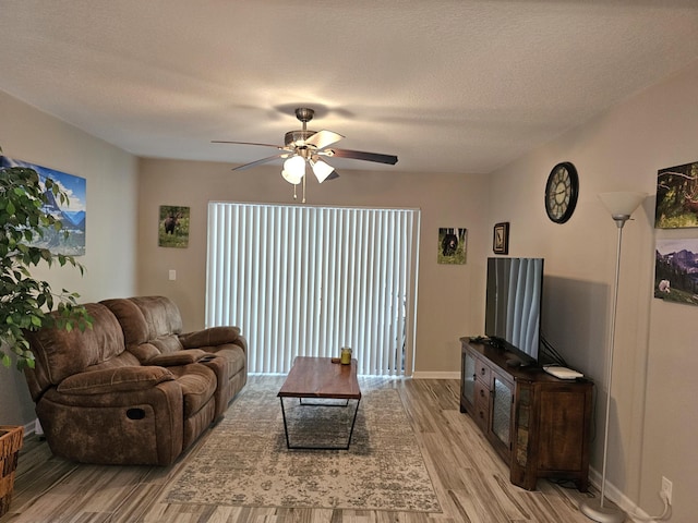 living room with ceiling fan, light hardwood / wood-style floors, and a textured ceiling