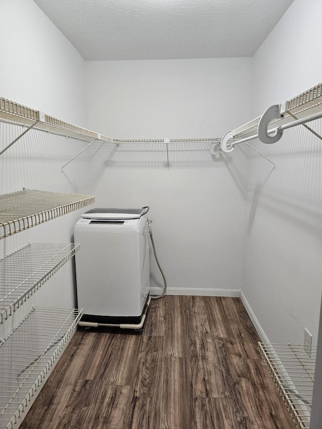 spacious closet with washer and dryer and dark wood-type flooring