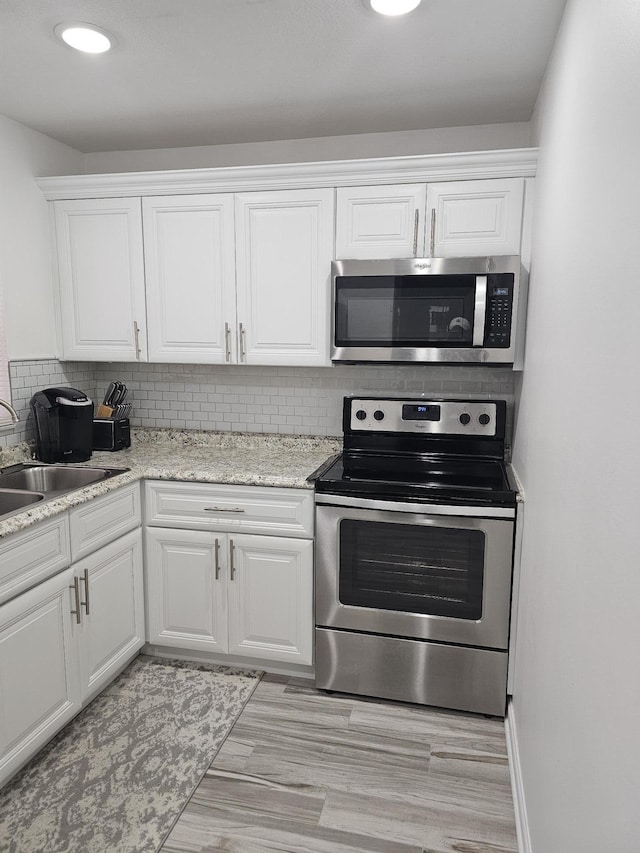 kitchen featuring tasteful backsplash, white cabinetry, sink, and stainless steel appliances