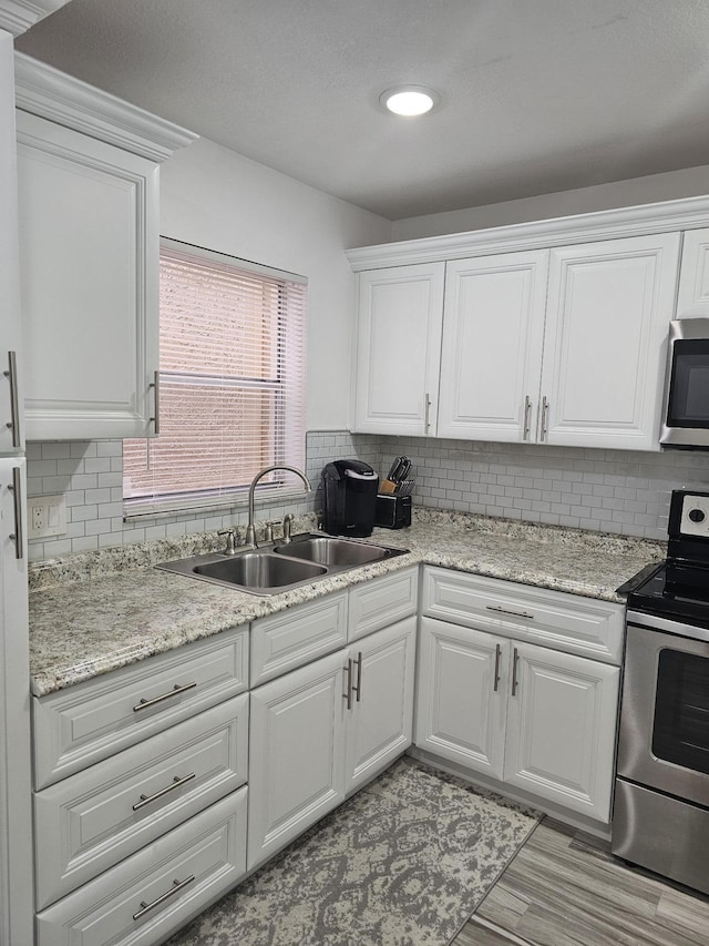 kitchen featuring white cabinets, stainless steel appliances, tasteful backsplash, and sink