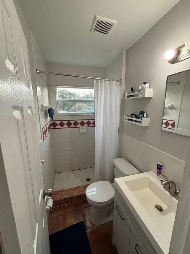 bathroom with curtained shower, vanity, tile walls, and toilet