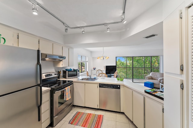 kitchen with sink, light tile patterned floors, a wealth of natural light, appliances with stainless steel finishes, and a chandelier