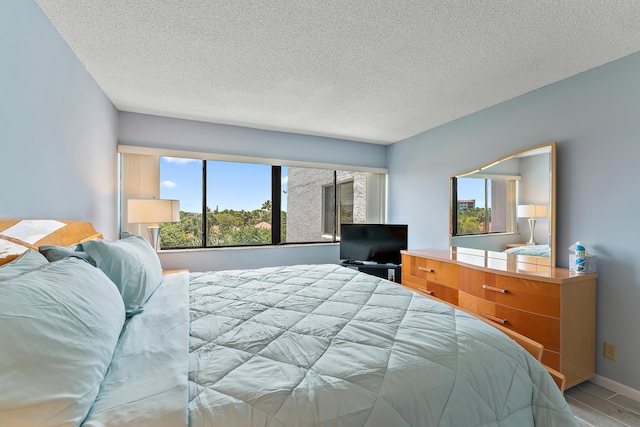 bedroom with a textured ceiling, light wood-type flooring, and multiple windows