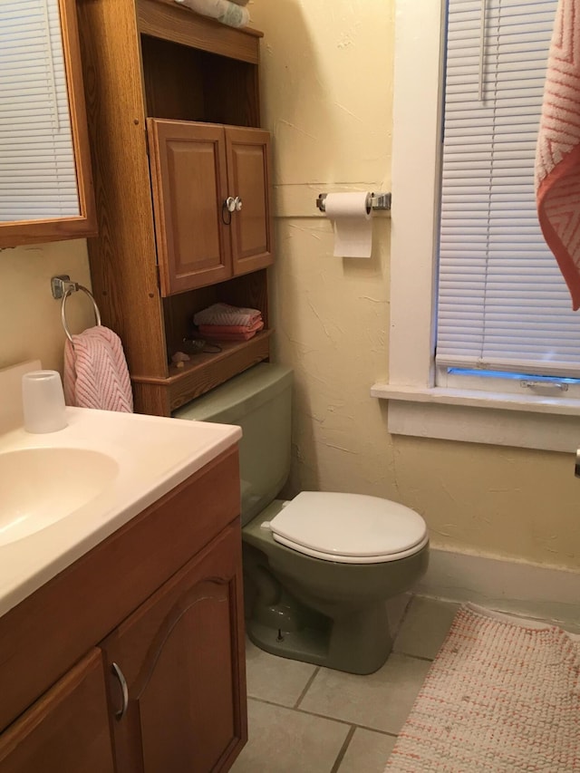 half bathroom with vanity, toilet, and tile patterned floors