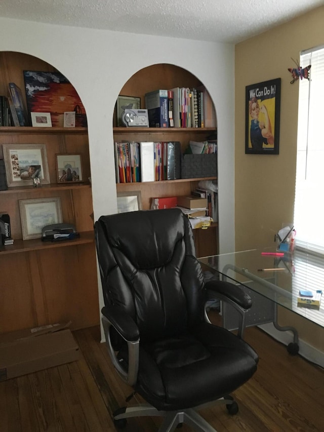 office space featuring a healthy amount of sunlight, built in shelves, a textured ceiling, and wood finished floors