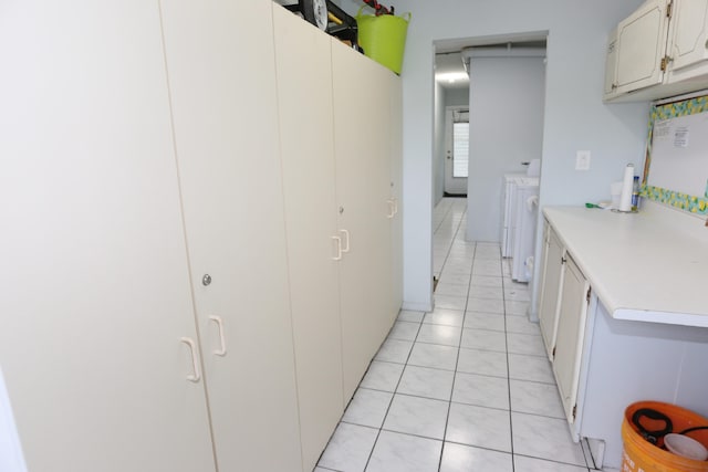 kitchen with white cabinets, washing machine and dryer, and light tile patterned floors