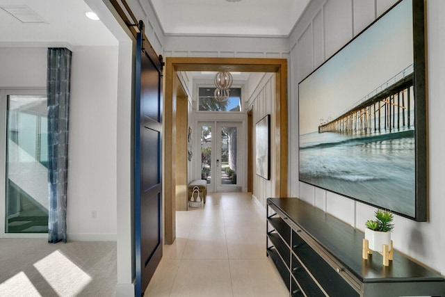 hallway with french doors, a barn door, and light tile patterned floors