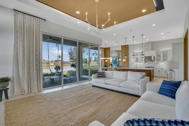 living room featuring sink, a water view, and an inviting chandelier