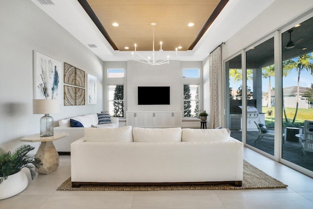 living room featuring a raised ceiling, a towering ceiling, and a chandelier