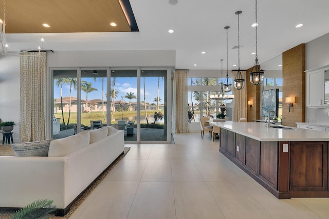 interior space with dark brown cabinets, a spacious island, sink, pendant lighting, and white cabinets