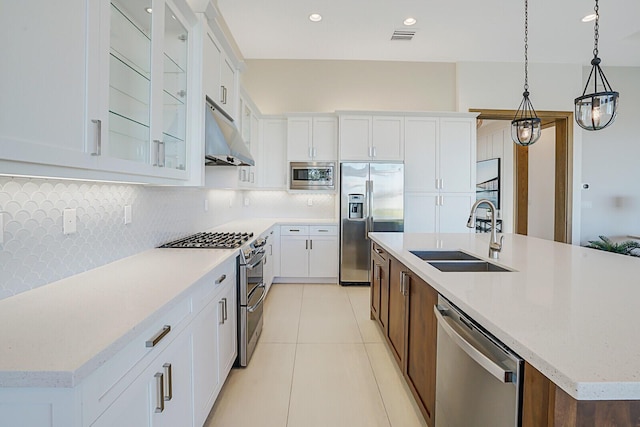 kitchen featuring white cabinets, built in appliances, a kitchen island with sink, and sink