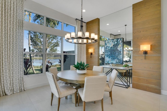 dining room with wooden walls, plenty of natural light, a water view, and a chandelier