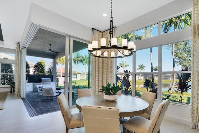 dining space featuring a water view and ceiling fan with notable chandelier