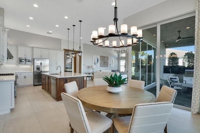 dining room with ceiling fan with notable chandelier, light tile patterned floors, and sink