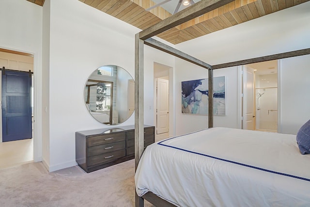 bedroom with beam ceiling, a barn door, wooden ceiling, and light carpet