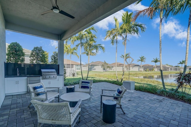 view of patio with area for grilling, ceiling fan, sink, a water view, and a grill