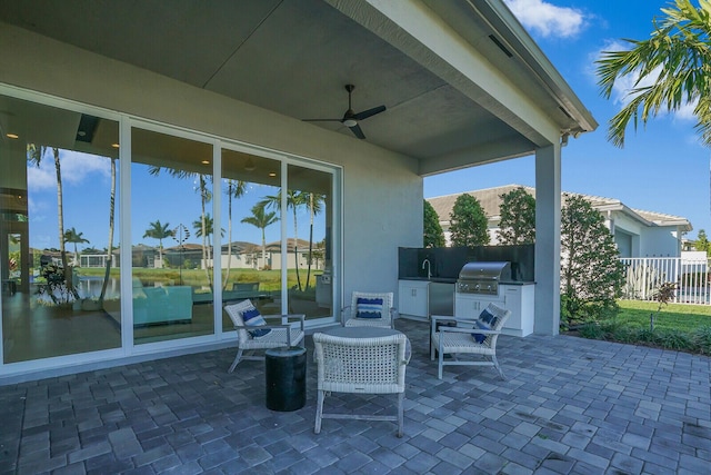 view of patio featuring ceiling fan, sink, an outdoor kitchen, a grill, and a water view