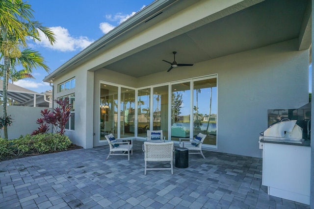 view of patio / terrace featuring a water view, ceiling fan, and exterior kitchen