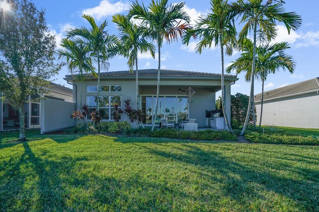 back of house with ceiling fan and a yard