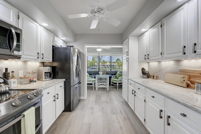 kitchen featuring tasteful backsplash, appliances with stainless steel finishes, white cabinetry, and light wood-style floors