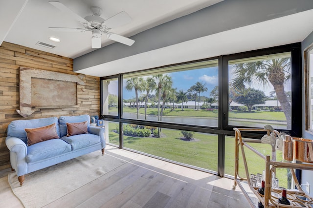 sunroom / solarium featuring ceiling fan and a water view