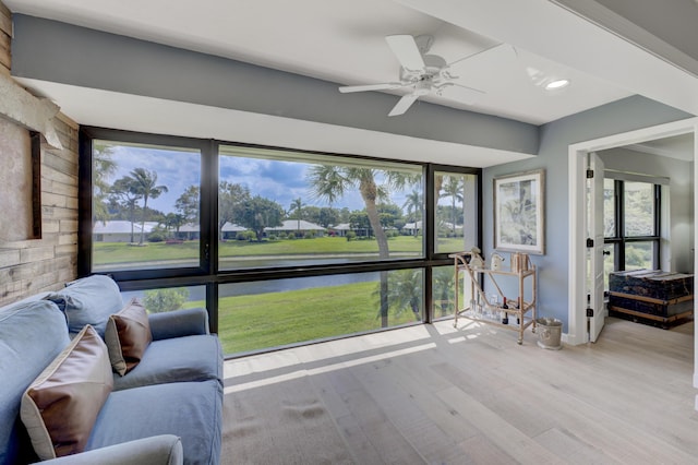 sunroom / solarium featuring a water view and a ceiling fan