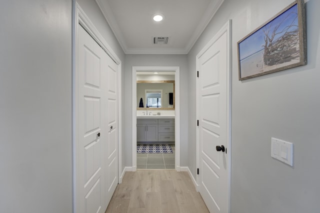 corridor with ornamental molding and light hardwood / wood-style flooring