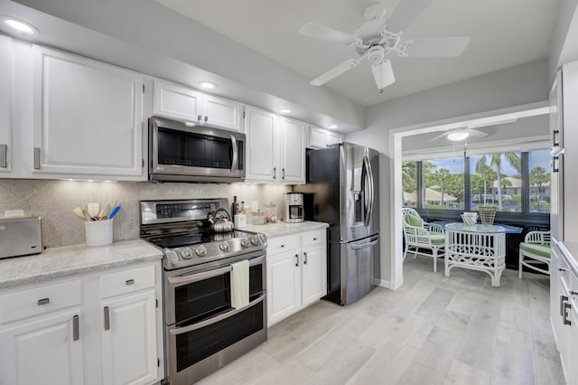 kitchen featuring white cabinets, a ceiling fan, decorative backsplash, light wood-style flooring, and stainless steel appliances